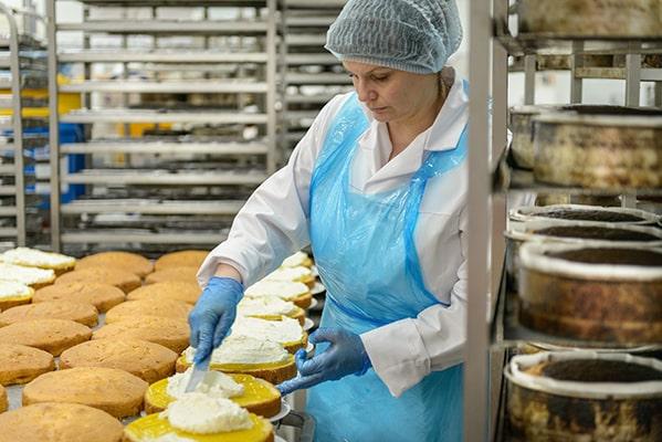 Pasteleira na cozinha industrial a usar utensilios da Enzitools